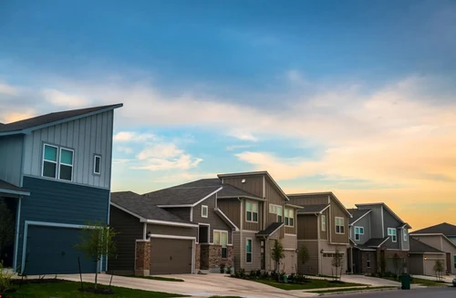 A sunset shines on a row of modern suburban homes in Austin, TX.