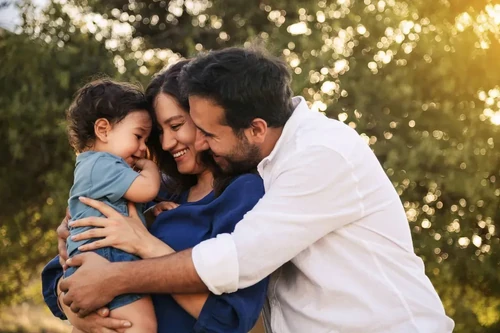 A young couple holds their baby and enjoys time together in their yard.