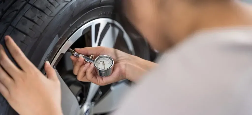 Person checking the air in a tire with a pressure gauge.