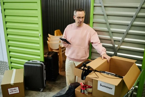 Man organizing moving boxes inside a self storage unit.