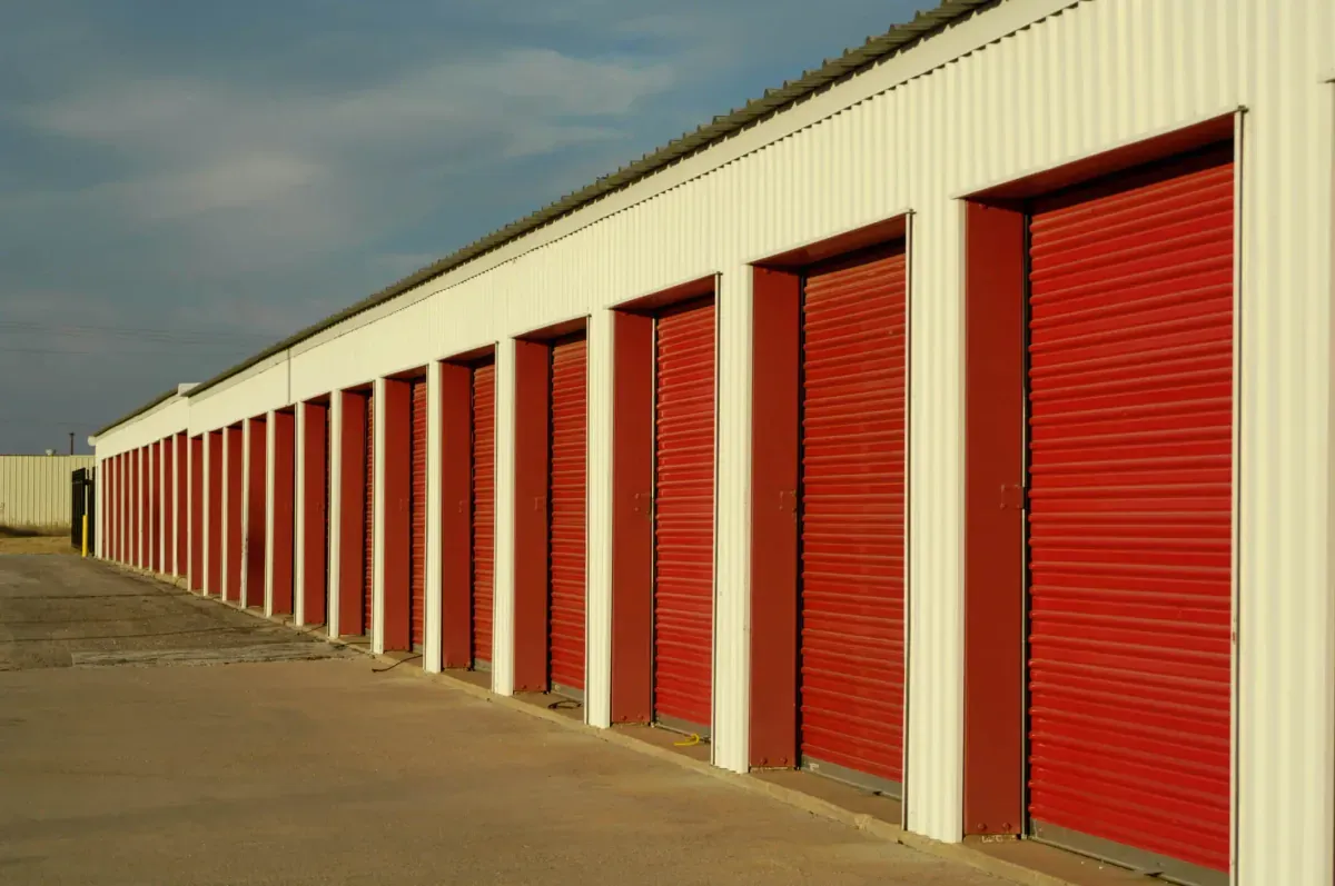 Exterior row of self storage units with red roll-up doors at storage facility.