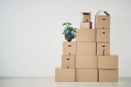 A group of cardboard boxes stacked on each other in front of a blank wall.